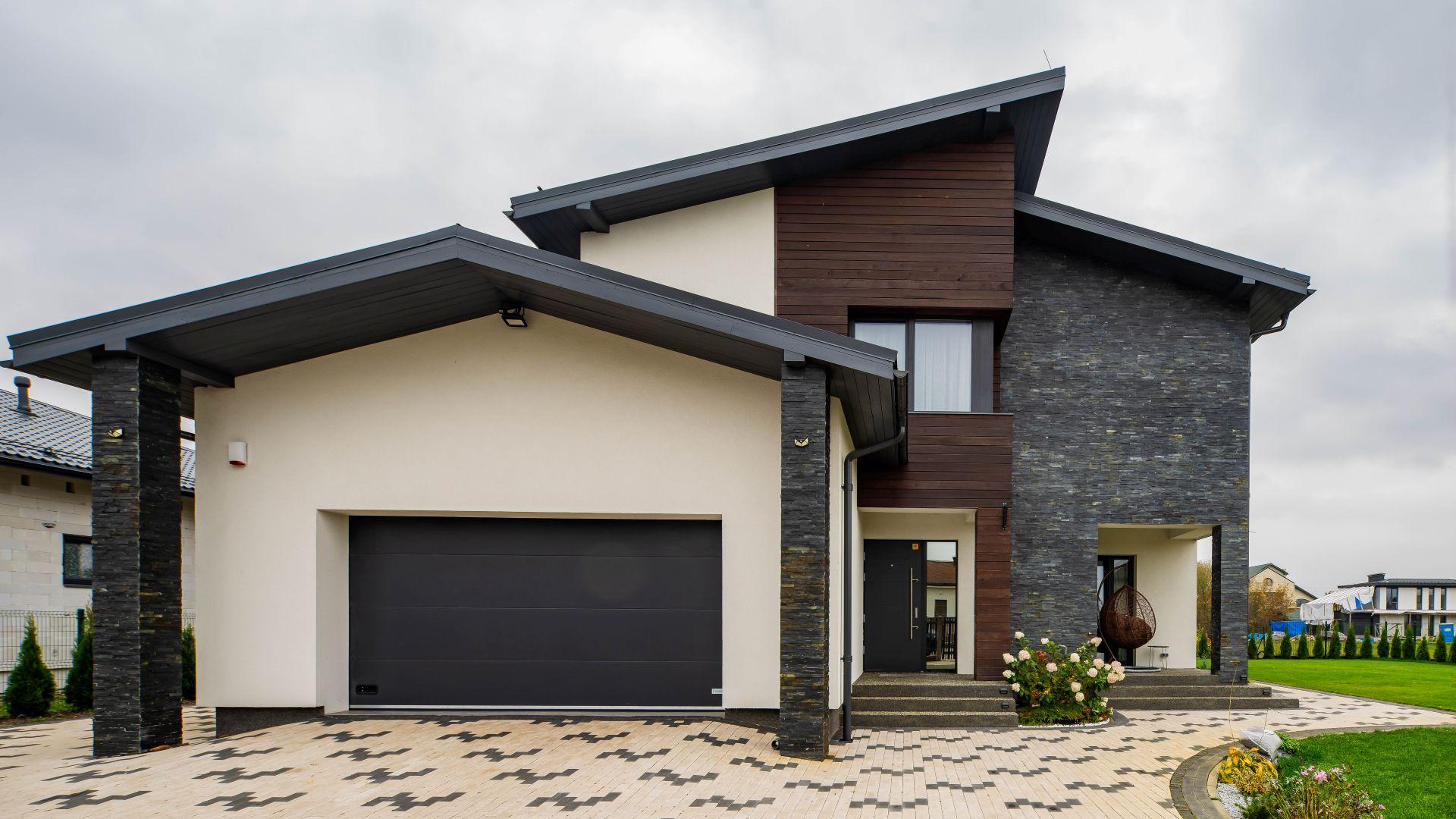 Modernes Einfamilienhaus mit dunklen Verblendern und heller Putzfassade zeigt zeitgemaesses Fassadendesign und architektonische Tiefe.