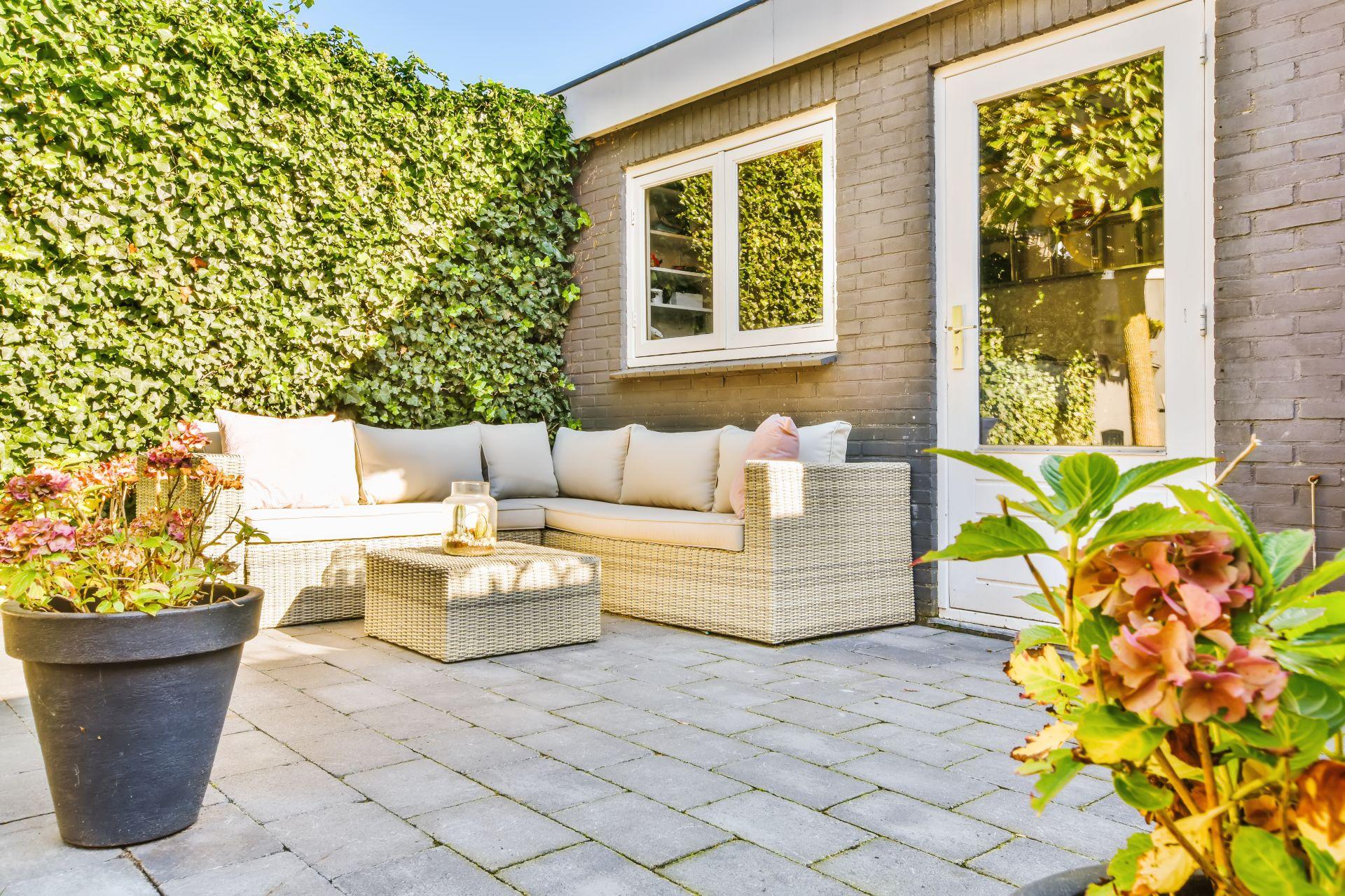 Helle Terrasse mit Verblender-Fassade und gepflegtem Garten als Beispiel fuer wohnliches Aussendesign und stilvolle Materialwahl.